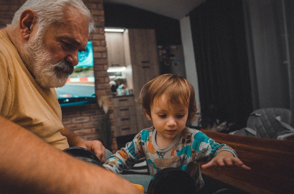 an older man and a young boy playing with a toy car