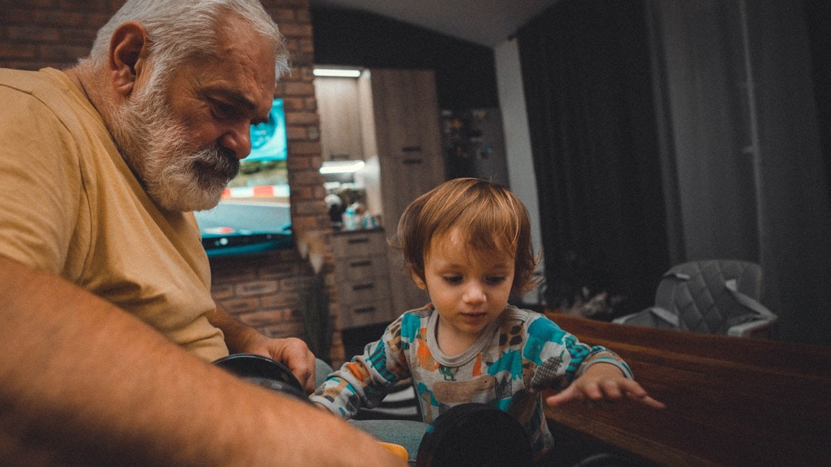 an older man and a young boy playing with a toy car